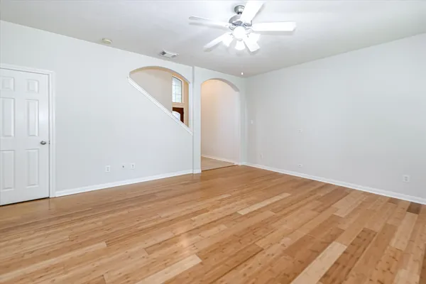 an empty room with wooden floor fan and windows