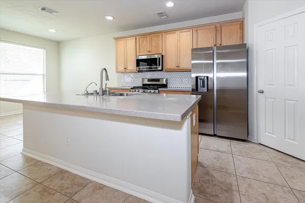 a kitchen with kitchen island a counter top space cabinets stainless steel appliances and a window