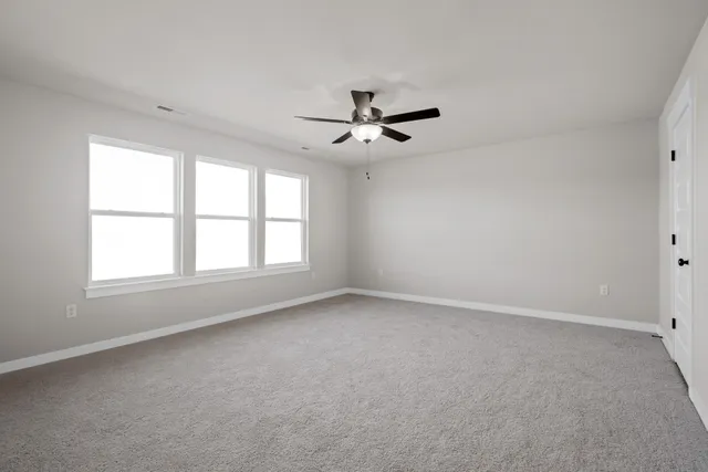 an empty room with a window and a ceiling fan
