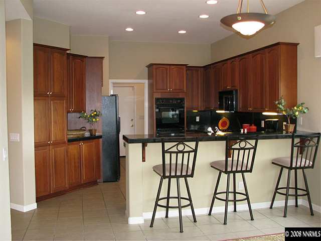 1609 Aspen Creek Road Reno, NV 89519 - Photo 3 of 9 a kitchen with stainless steel appliances kitchen island granite countertop a refrigerator a stove a microwave oven with a dining table and chairs