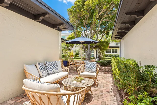 a view of patio with couches table and chairs under an umbrella with a small yard