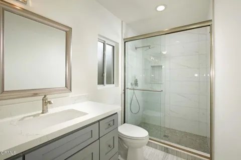 a bathroom with a shower sink vanity mirror and toilet