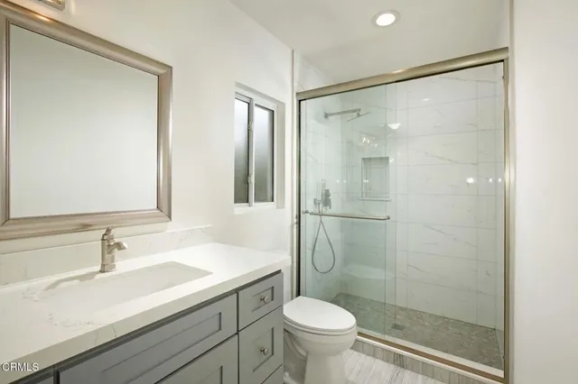 a bathroom with a shower sink vanity mirror and toilet