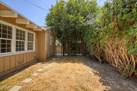 a view of a backyard with large trees and wooden fence