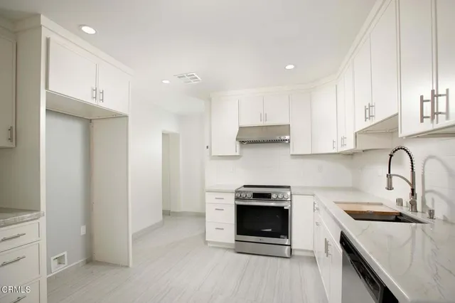 a kitchen with stainless steel appliances granite countertop a stove a sink and a refrigerator