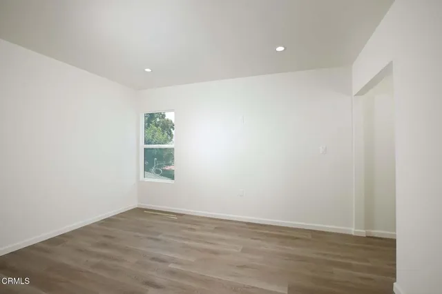 an empty room with wooden floor and window