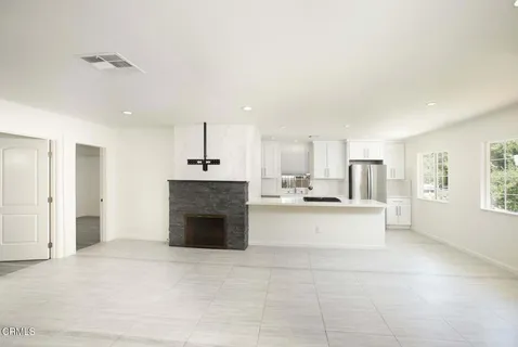 a large white kitchen with a stove a sink dishwasher and a fireplace with wooden floor