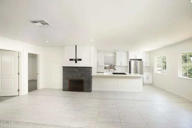 a large white kitchen with a stove a sink dishwasher and a fireplace with wooden floor