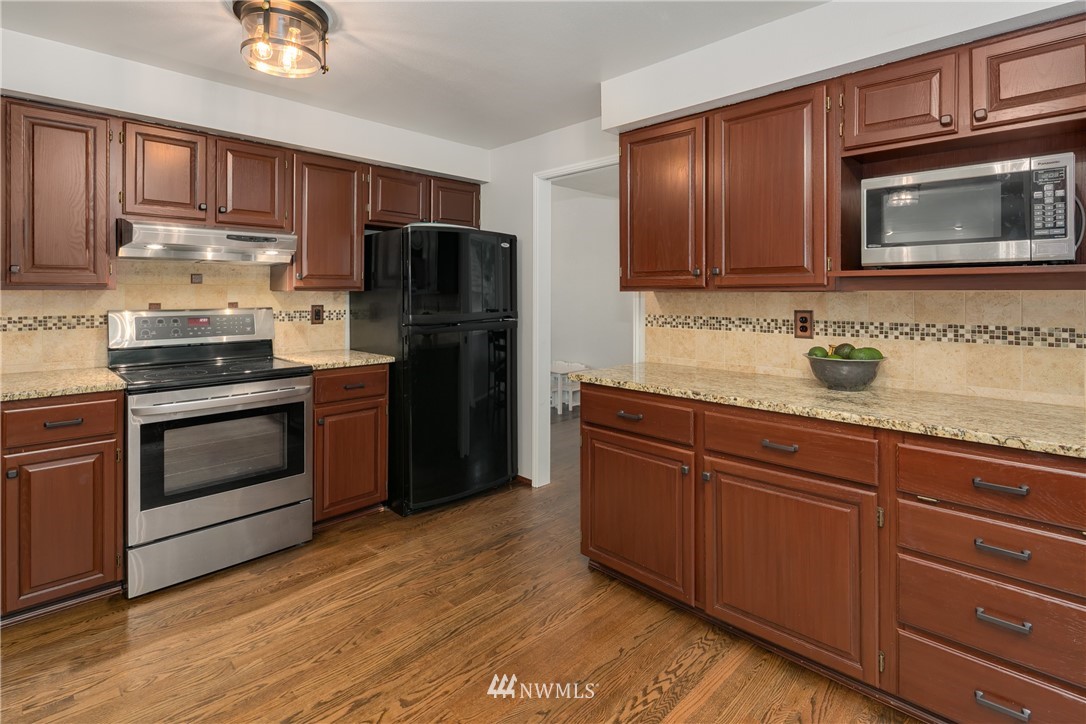 8 170th Place Southwest Bothell, WA 98012 - Photo 8 of 21 a kitchen with granite countertop stainless steel appliances and wooden cabinets