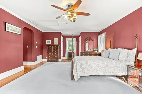 a bedroom with a large bed and chandelier fan