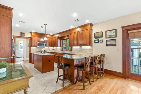 a dining area with stainless steel appliances kitchen island granite countertop wooden floor dining table and chairs