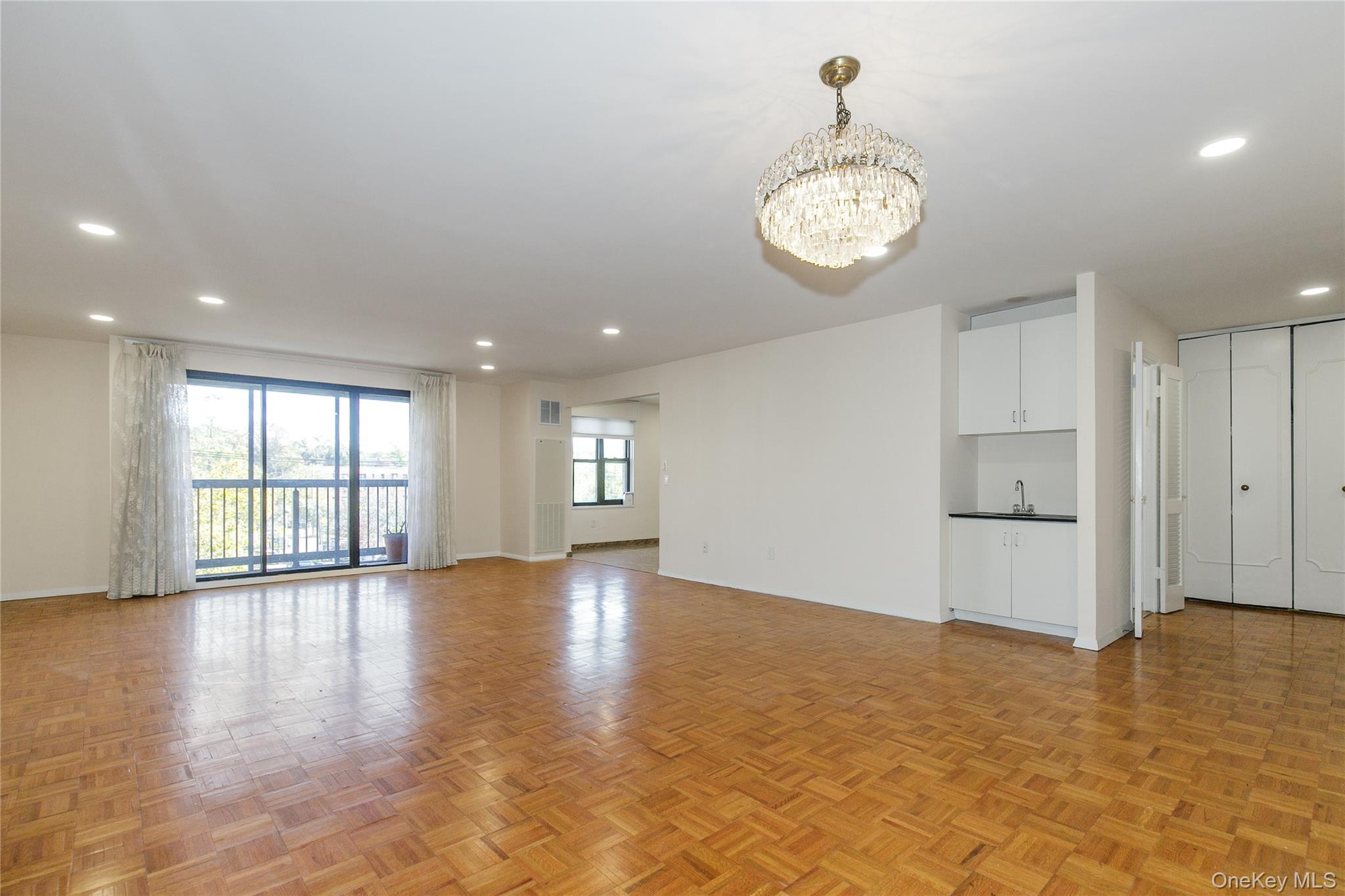 12 Bond Street, Unit 4C Great Neck, NY 11021 - Photo 7 of 34 Unfurnished living room with recessed lighting and a chandelier