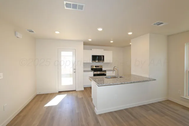 a kitchen with granite countertop a sink cabinets and wooden floor