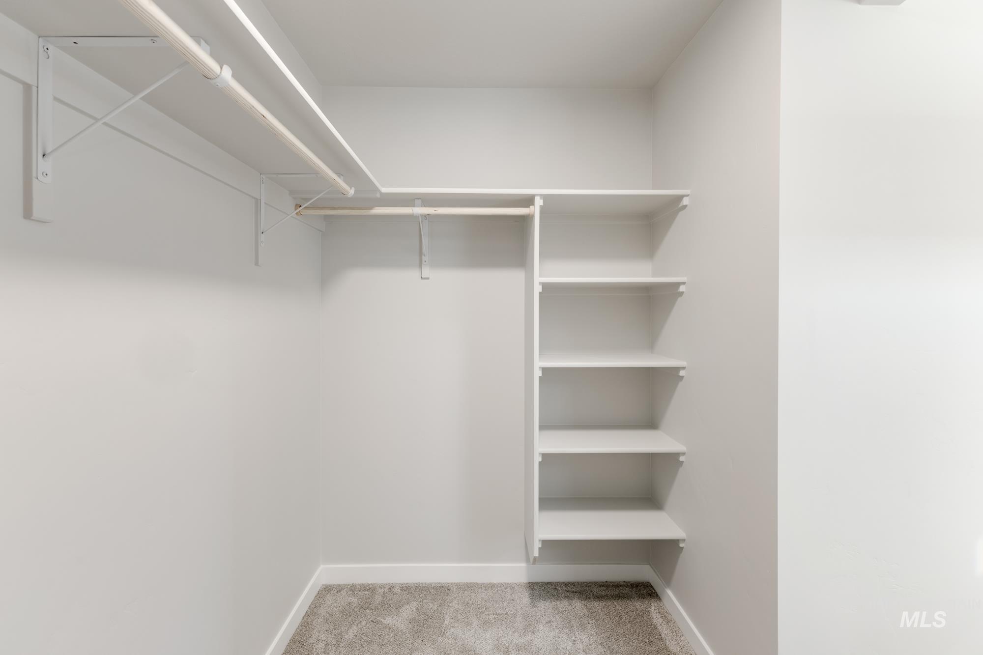 12853 Decatur Street Nampa, ID 83651 - Photo 24 of 24 Walk-in closet featuring built-in shelving, two clothing rods, white walls, white baseboards, and carpeted flooring
