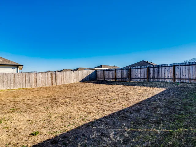 a view of a house with backyard and wooden fence