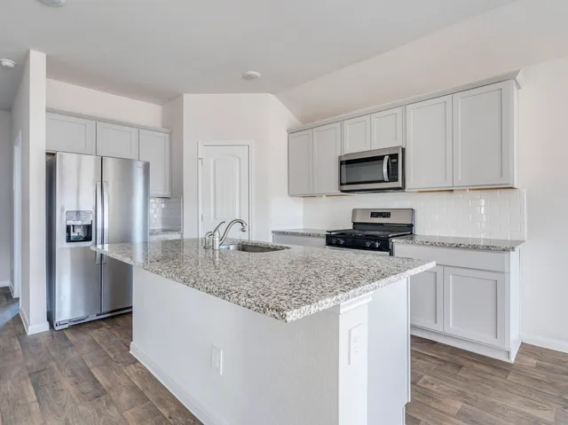 a kitchen with a granite counter tops refrigerator and microwave