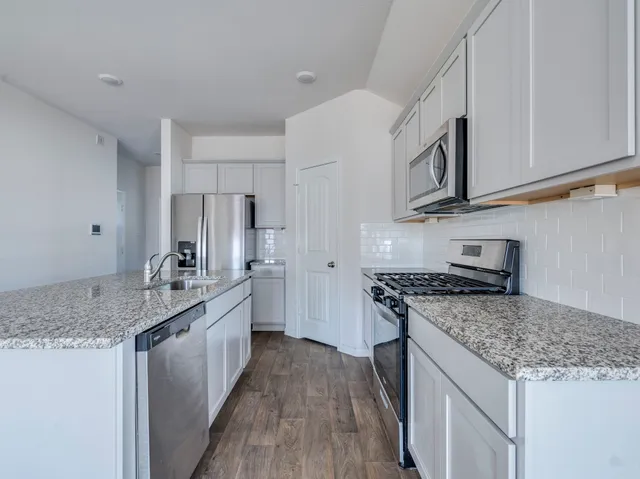 a kitchen with stainless steel appliances granite countertop a sink stove and cabinets