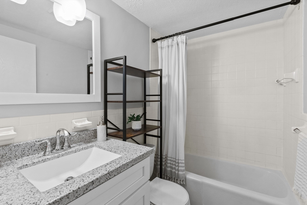 157 Franklin Street, Unit A10 Stoneham, MA 02180 - Photo 8 of 10 a bathroom with a granite countertop sink toilet and shower