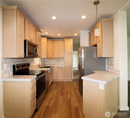 a kitchen with a sink a counter top space stainless steel appliances and cabinets