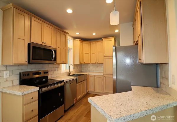 a kitchen with stainless steel appliances granite countertop a sink a stove a refrigerator a microwave oven with cabinets and wooden floor