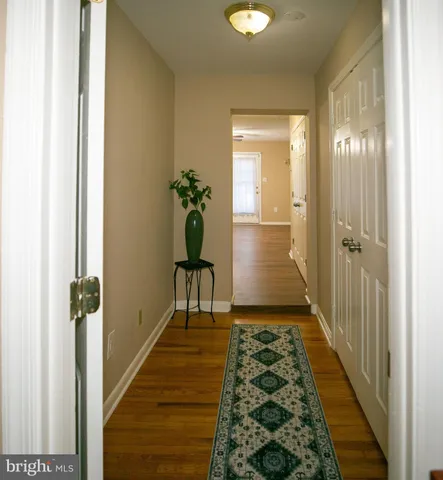 a view of a hallway with wooden floor and a dining room