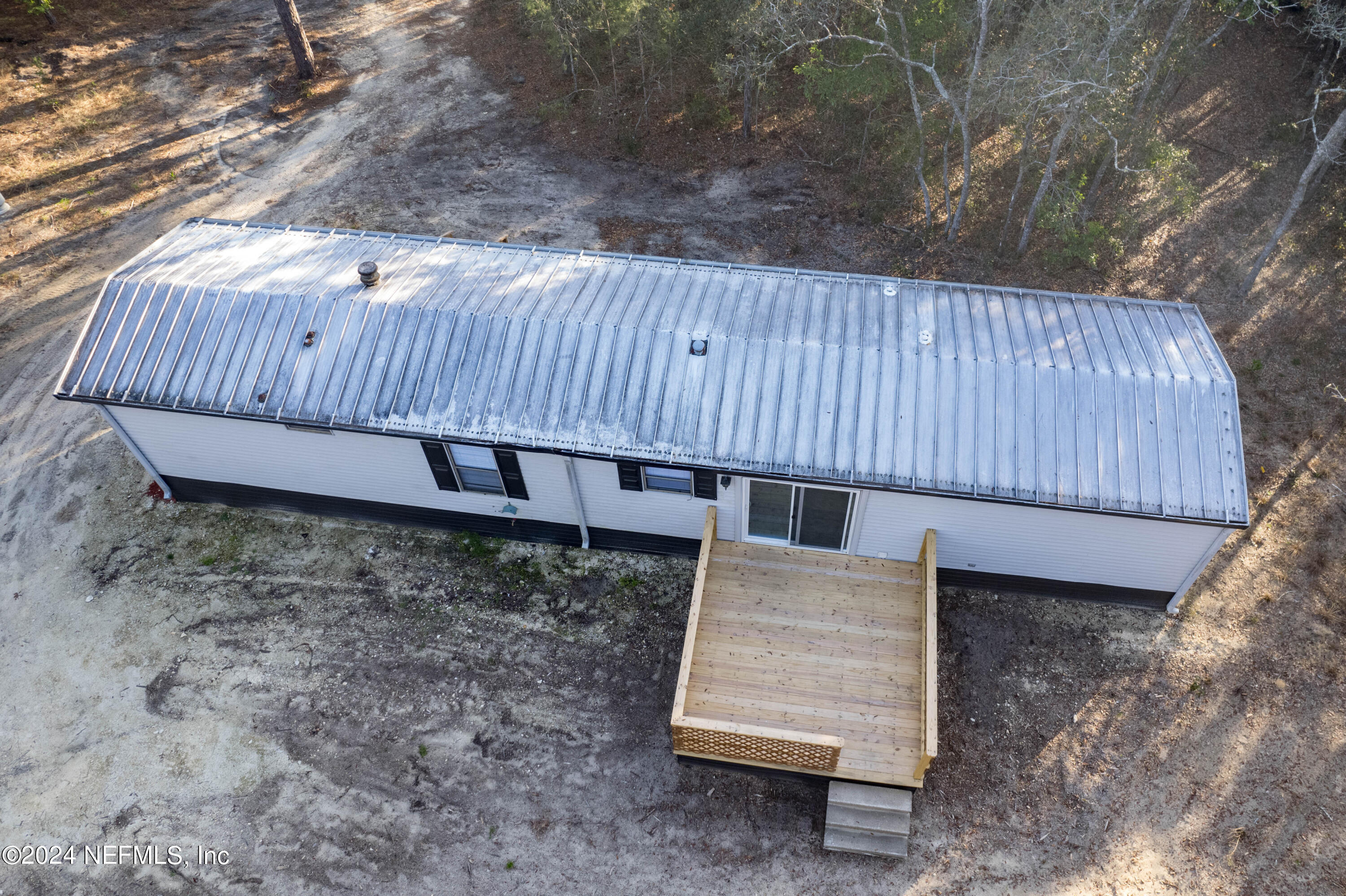 6787 Deer Springs Road Keystone Heights, FL 32656 - Photo 15 of 54 a view of a backyard with a small deck and wooden fence