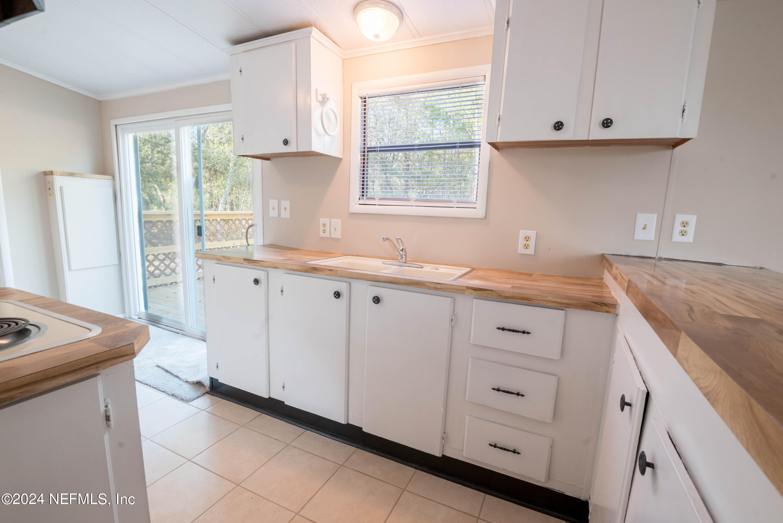 6787 Deer Springs Road Keystone Heights, FL 32656 - Photo 37 of 54 a kitchen with granite countertop white cabinets and a window