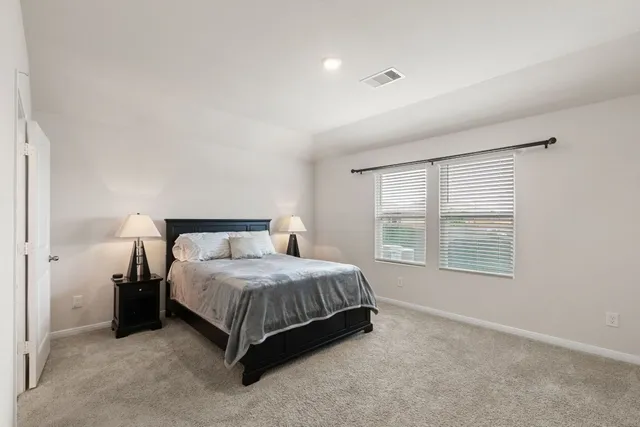 a bedroom with a bed lamp and a large window
