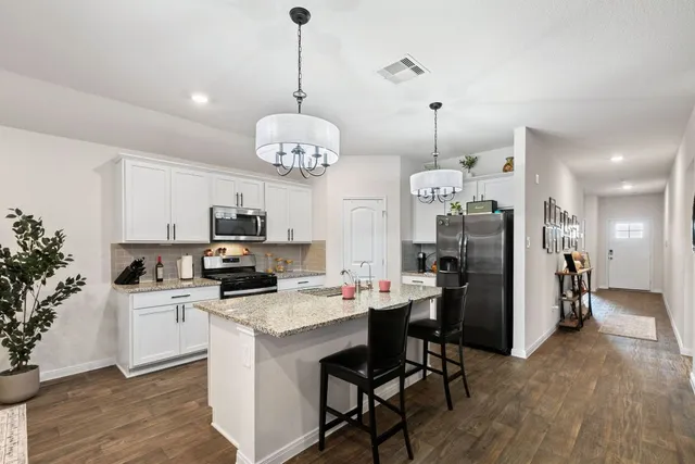 a kitchen that has a lot of cabinets a sink and appliances