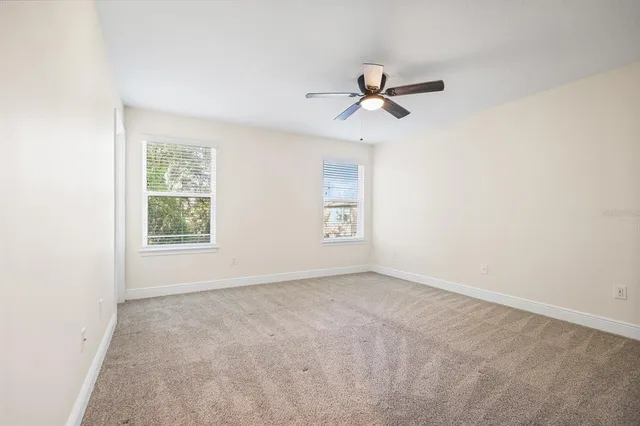 an empty room with windows and fan