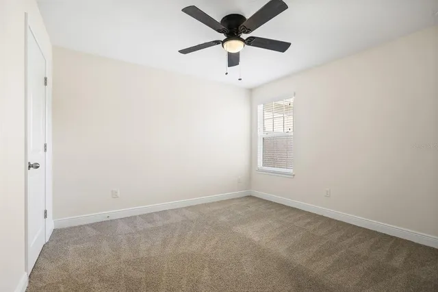 an empty room with a window and a fan