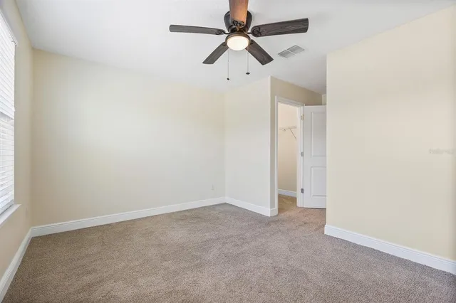 an empty room with a window and a fan