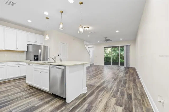 a kitchen with a sink wooden floor and white cabinets
