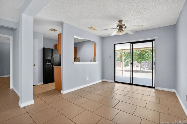 a view of an empty room with window and chandelier fan