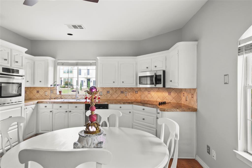4020 Mediterranean Street Rockwall, TX 75087 - Photo 10 of 29 a kitchen with stainless steel appliances kitchen island granite countertop a sink dishwasher and white cabinets with wooden floor