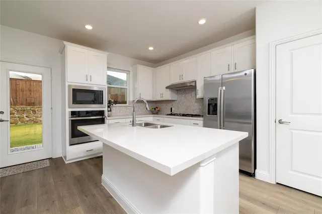a kitchen with stainless steel appliances a refrigerator sink and microwave