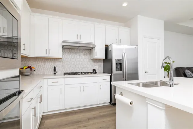 a kitchen with white cabinets and stainless steel appliances