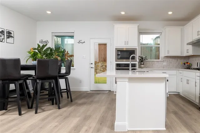 a kitchen with a table chairs refrigerator and microwave