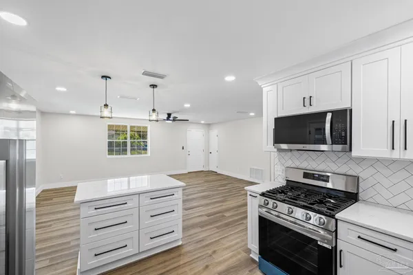 a kitchen with granite countertop a refrigerator and a stove top oven