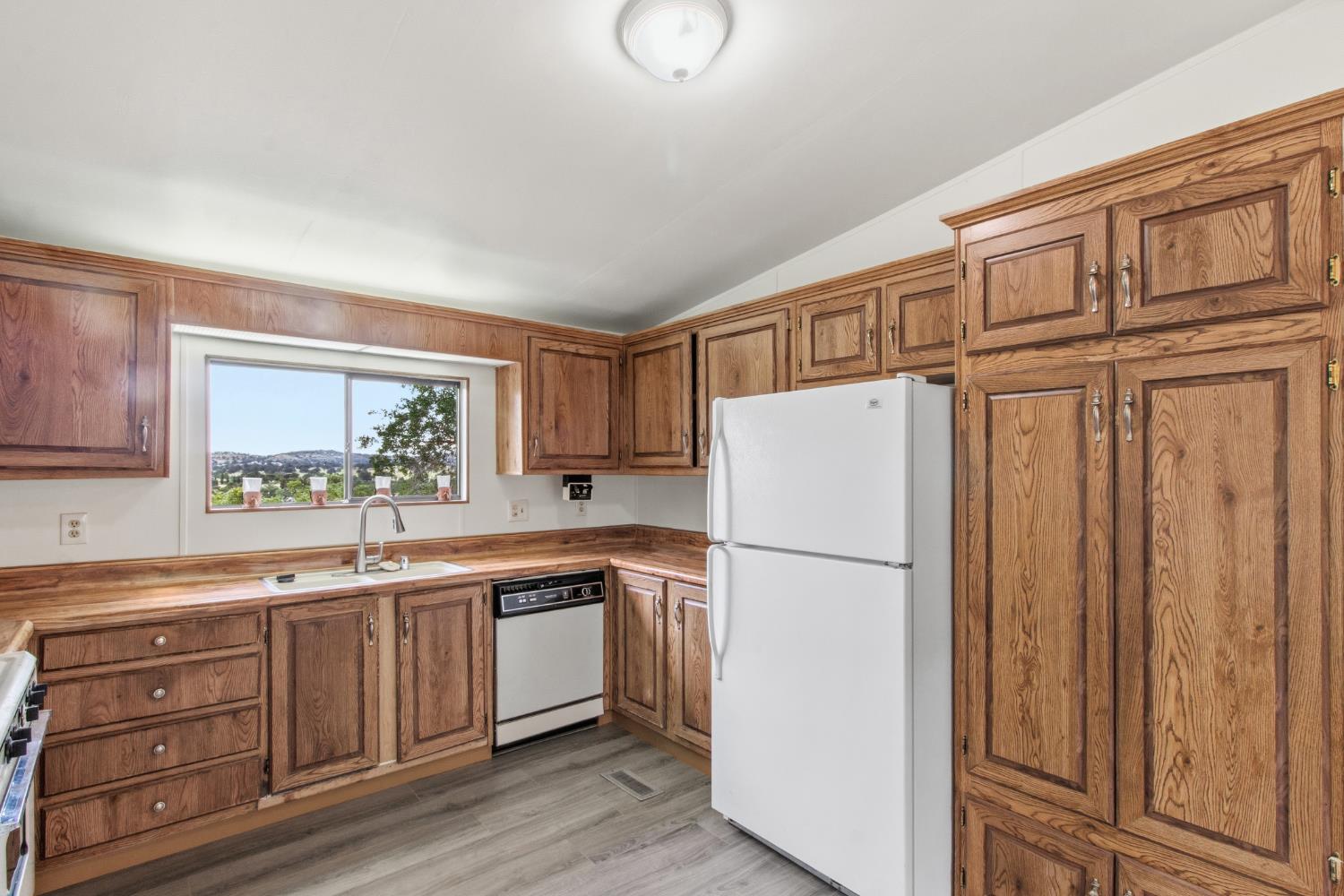 10580 Thompson Way Valley Springs, CA 95252 - Photo 18 of 64 a white refrigerator freezer sitting inside of a kitchen with stainless steel appliances granite countertop cabinets and a refrigerator