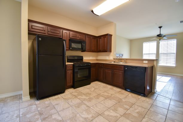 15918 Windermere Drive, Unit 315 Pflugerville, TX 78660 - Photo 3 of 13 a kitchen with granite countertop a refrigerator and a sink