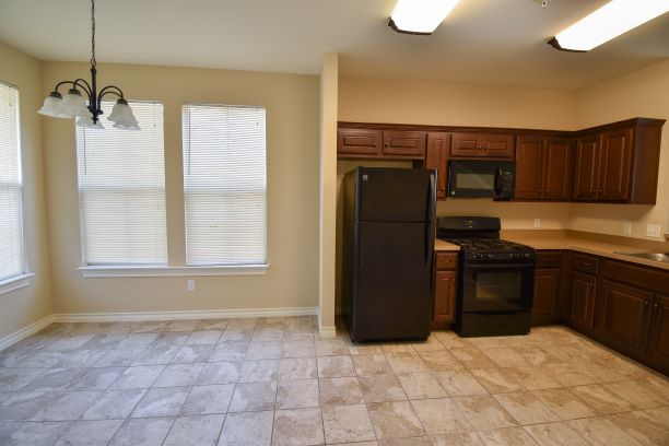 15918 Windermere Drive, Unit 315 Pflugerville, TX 78660 - Photo 4 of 13 a kitchen with granite countertop a refrigerator and a stove top oven