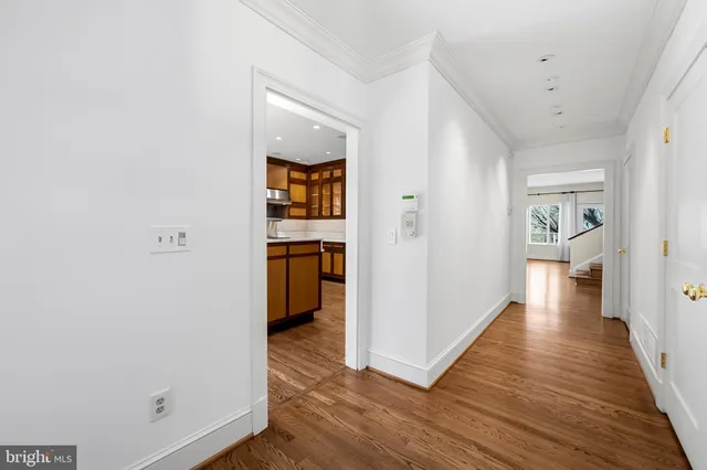 a view of a hallway with wooden floor and a bathroom