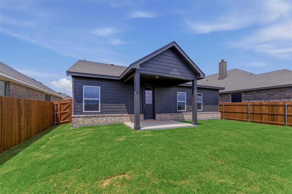 3504 Helena Street Gainesville, TX 76240 - Photo 16 of 19 Spacious rear yard with a covered patio, dark siding, and a partial stone facade