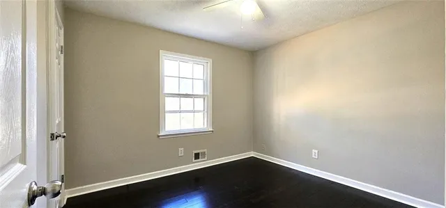 an empty room with wooden floor and windows
