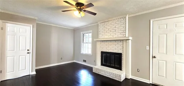 an empty room with wooden floor fireplace and windows
