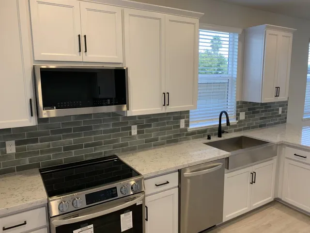 a kitchen with granite countertop a sink stove and microwave