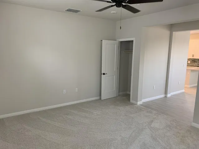 an empty room with a ceiling fan and carpet