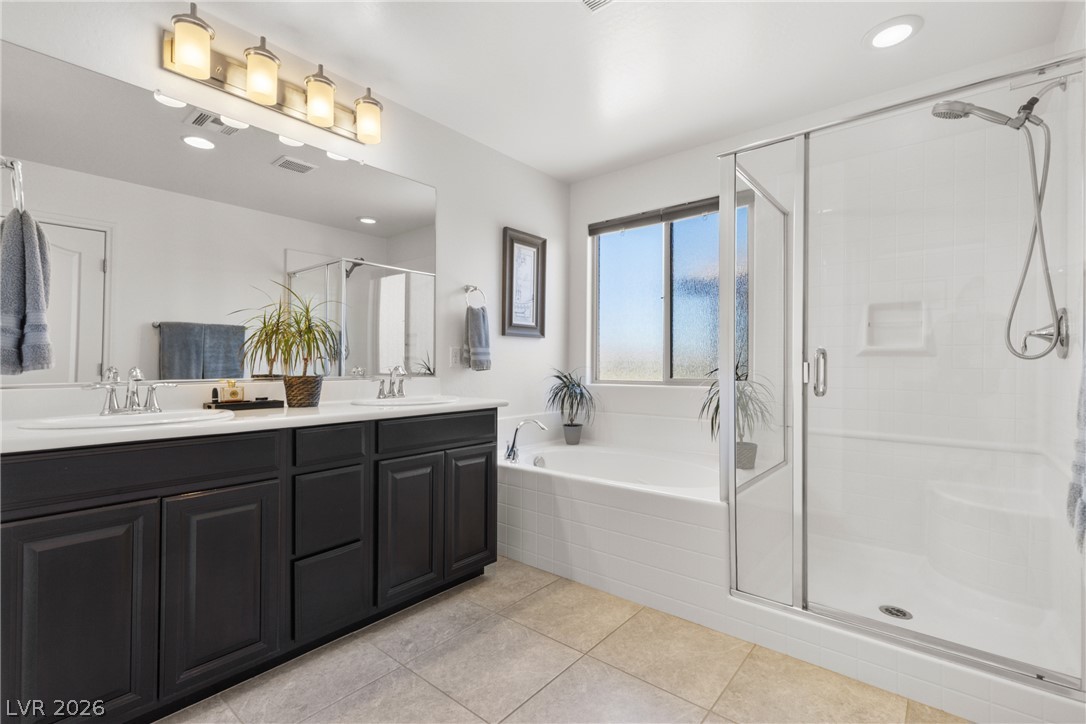 891 Earth Luster Road Las Vegas, NV 89178 - Photo 15 of 48 A well-appointed primary bathroom showcases dual vanities, a deep soaking tub, and a separate glass-enclosed shower.