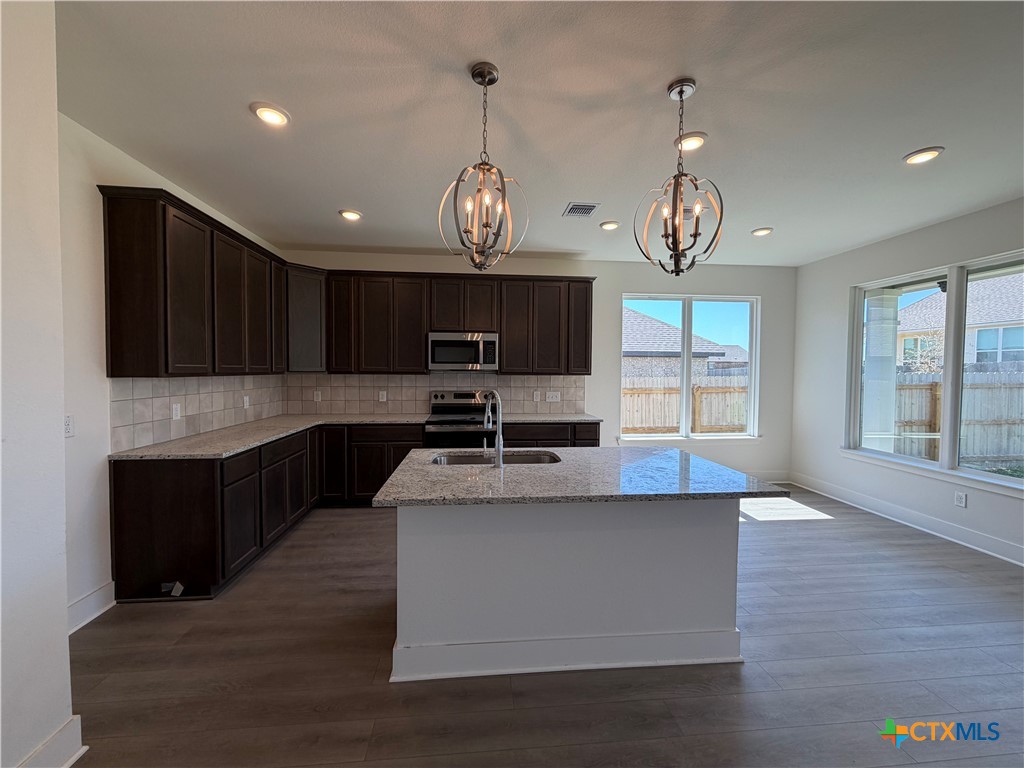 1985 Mercer Street Nolanville, TX 76559 - Photo 16 of 24 a large kitchen with stainless steel appliances kitchen island granite countertop a table and chairs in it